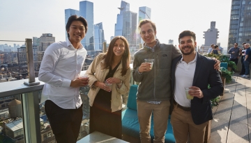 Four individuals, with drinks in their hands, smiling for the camera.